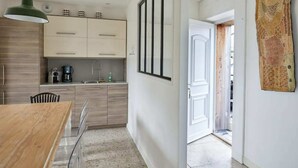 Une cuisine moderne avec des meubles de couleur bois clair, une machine à café et un coin repas comprenant une table et des chaises en bois.