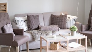 Un salon moderne comprenant un canapé, des fauteuils, une table basse et une table d’appoint.