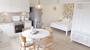 Une cuisine moderne avec des armoires blanches, un réfrigérateur en acier inoxydable et une table à manger avec des chaises.