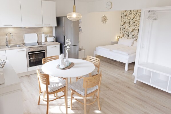 Une cuisine moderne avec des armoires blanches, un réfrigérateur en acier inoxydable et une table à manger avec des chaises.