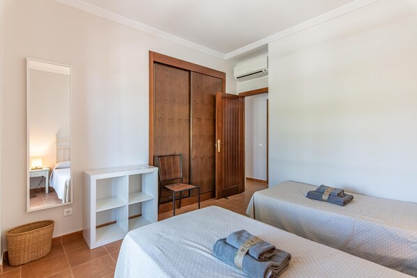 Une chambre d’hôtel avec deux lits, une armoire en bois, une chaise, une petite table et un miroir.