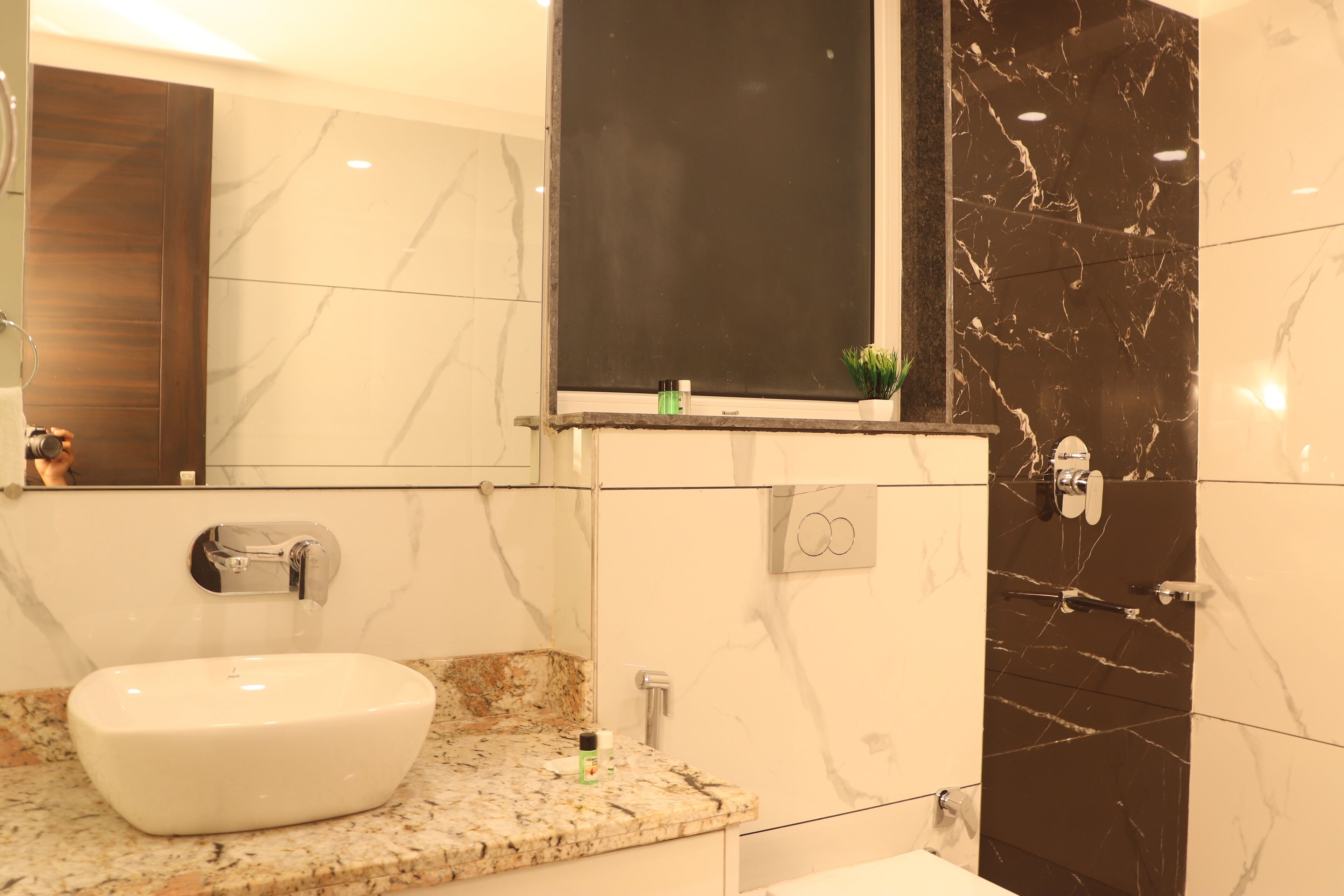 A bathroom with a white sink, marble walls, and a dark marble accent wall.