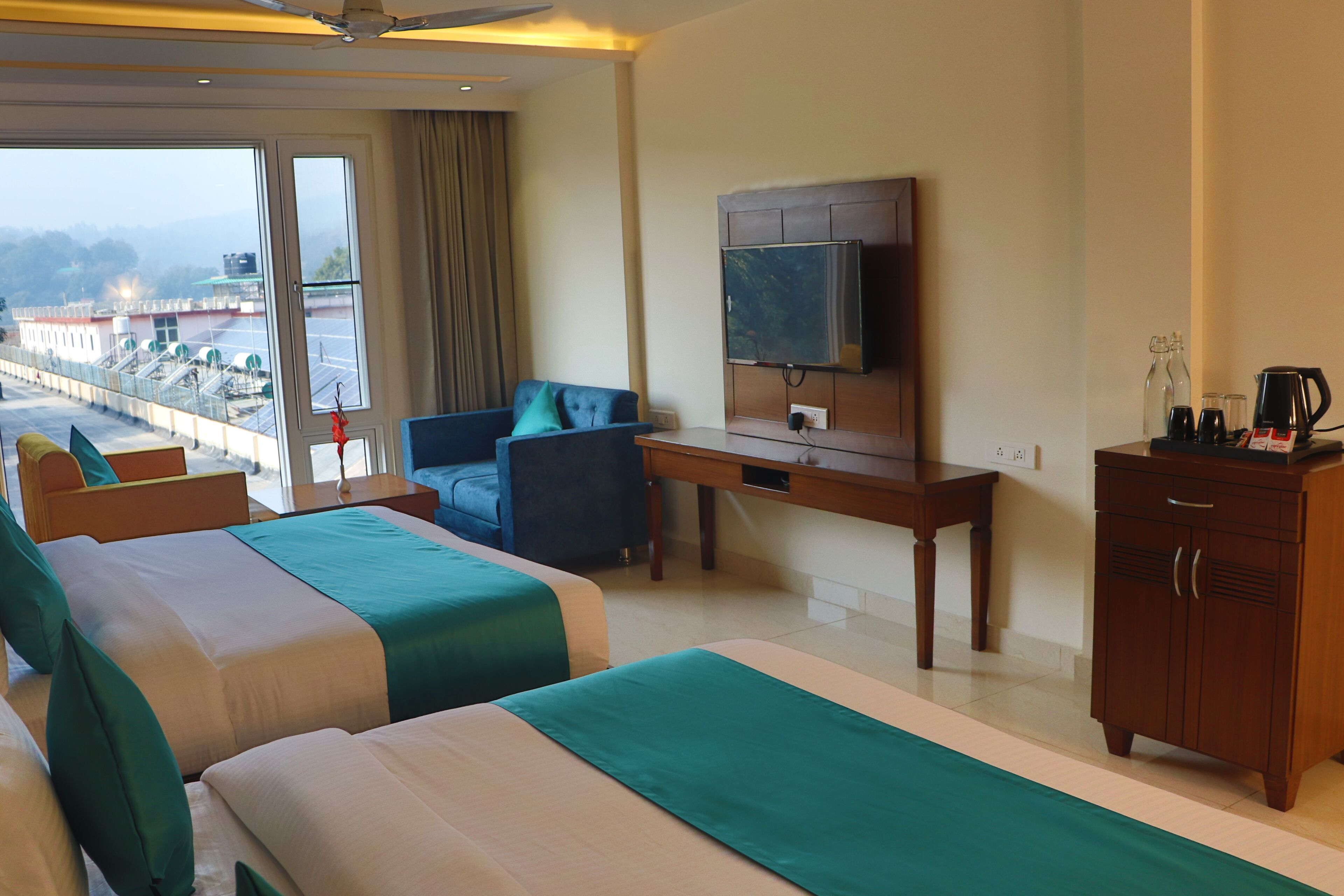 Une chambre d’hôtel avec deux lits, un bureau, une télévision et une vue sur la ville.