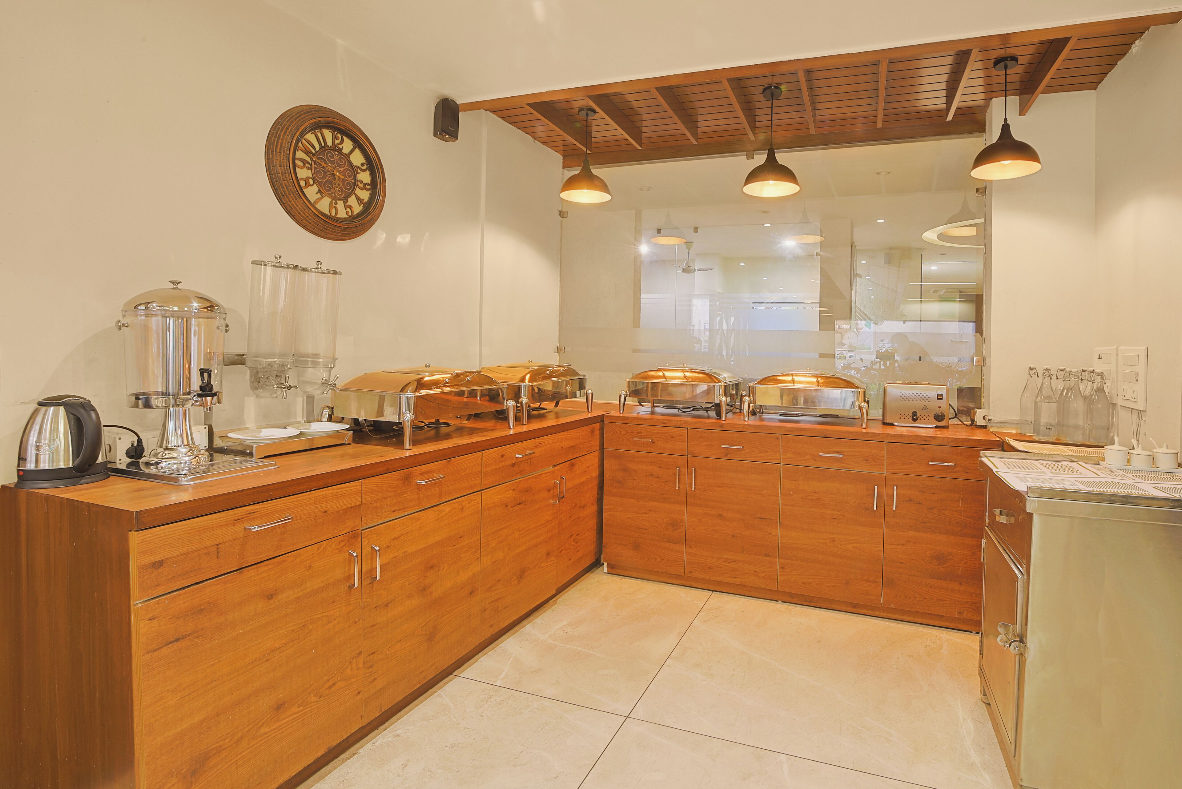 A modern kitchen with wooden cabinets, a coffee station, and a large window.