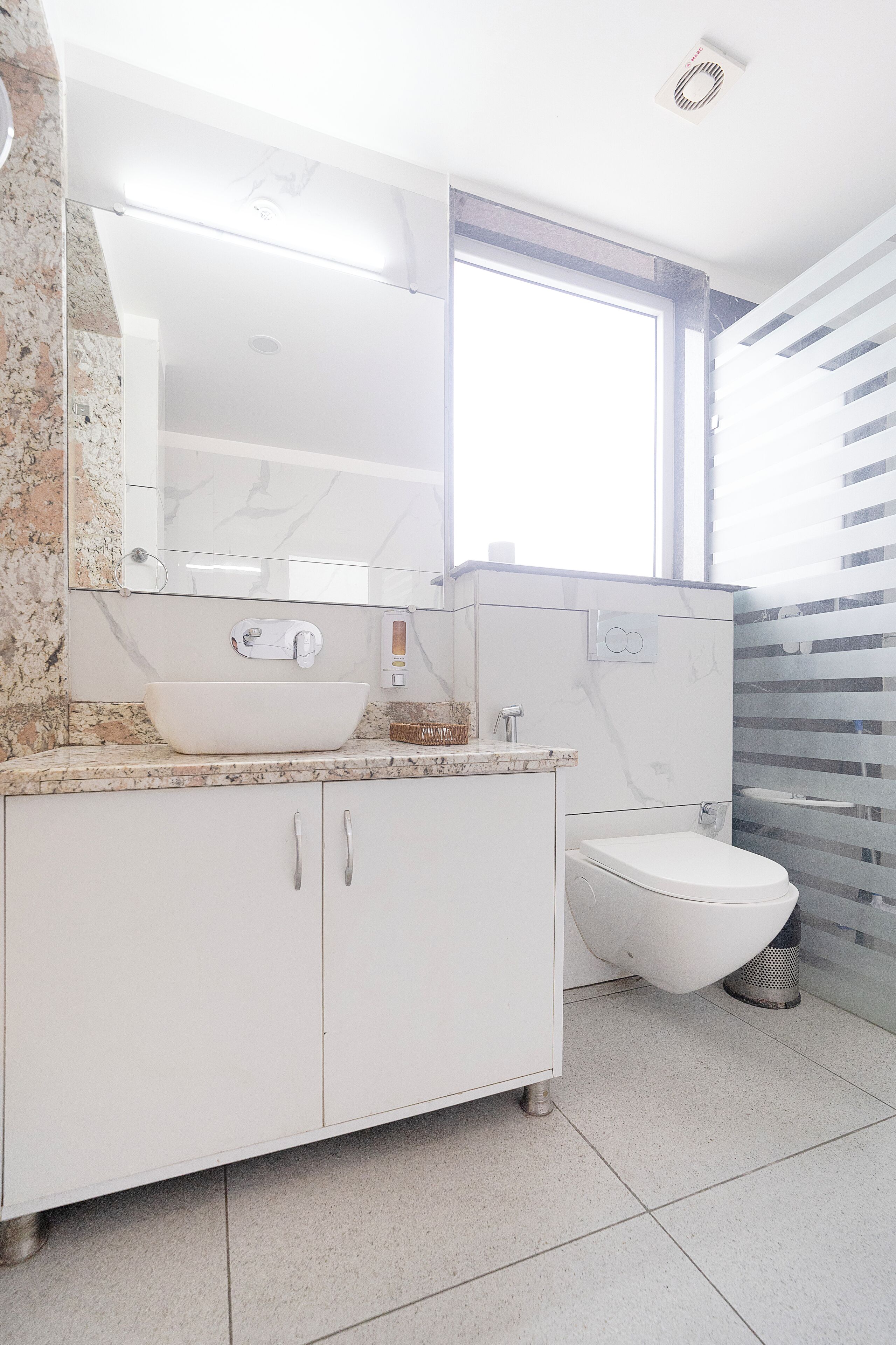 A modern bathroom with a white sink, vanity, and toilet.