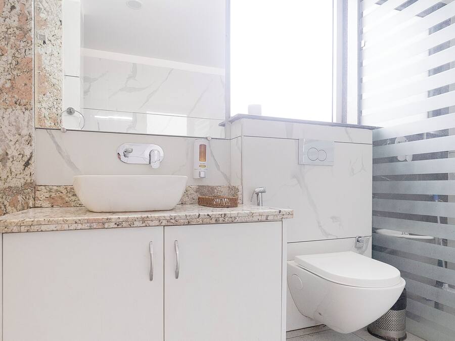 A modern bathroom with a white sink, vanity, and toilet.