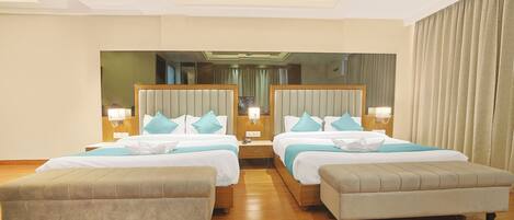 Habitación de hotel con dos camas, un espejo grande, cabeceros de madera y suelo de madera.