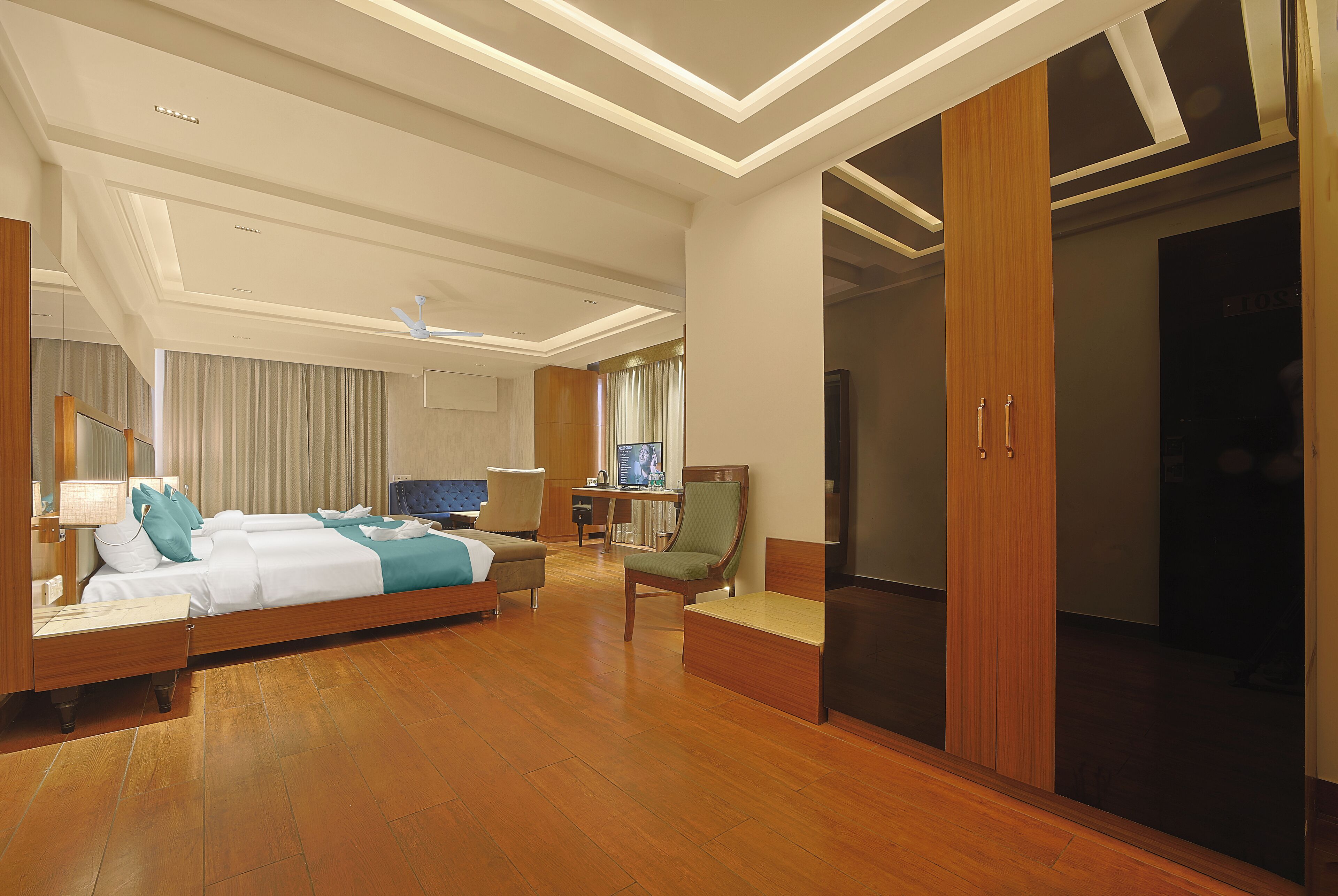 A hotel room with a bed, a desk, a chair, a wardrobe, and a television.
