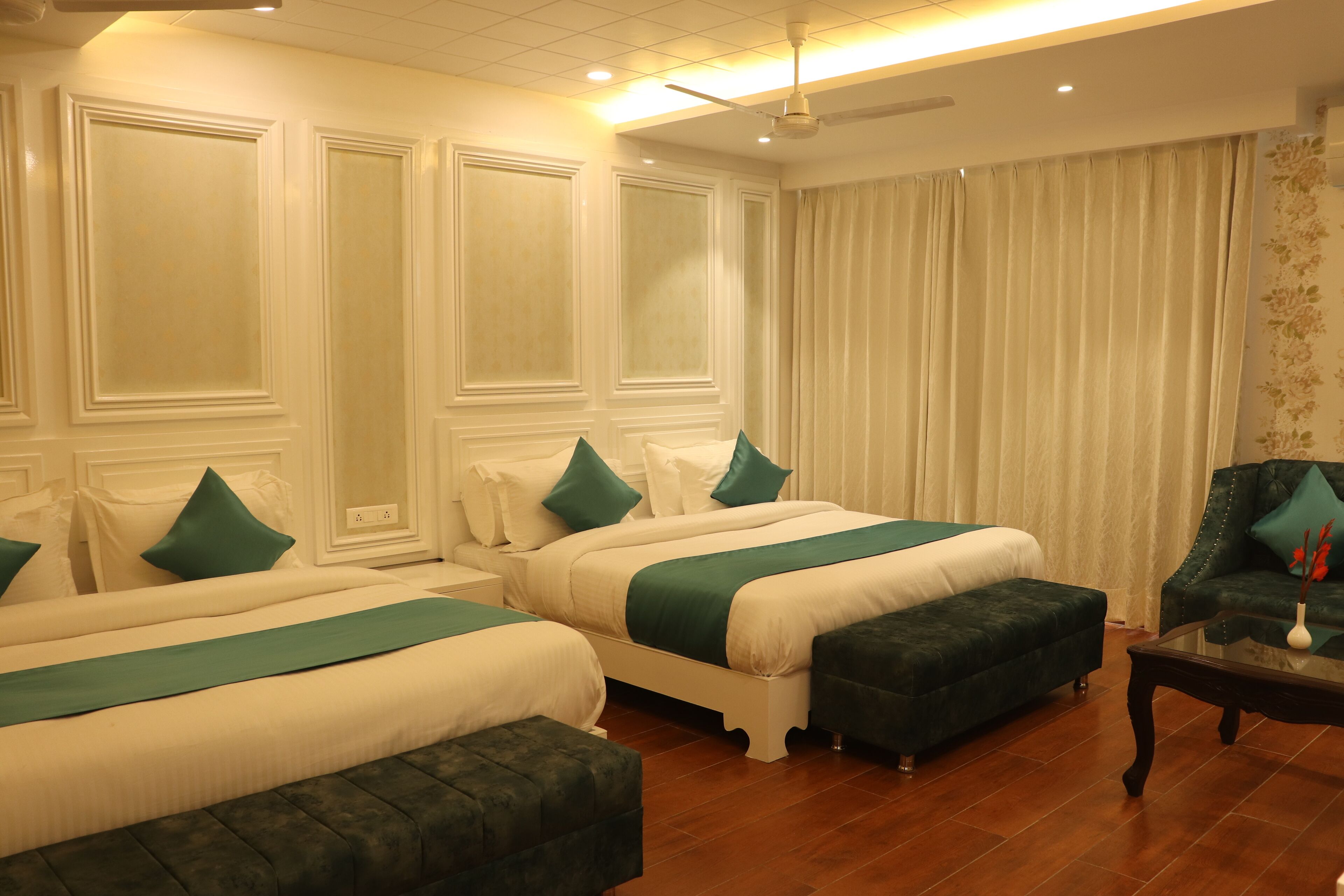 A hotel room with two beds, a sofa, and a small table.