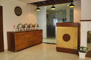 A reception area with a wooden cabinet, a clock, and pendant lighting. - Hotel Green - Behind Parmarth Niketan (Rishikesh)