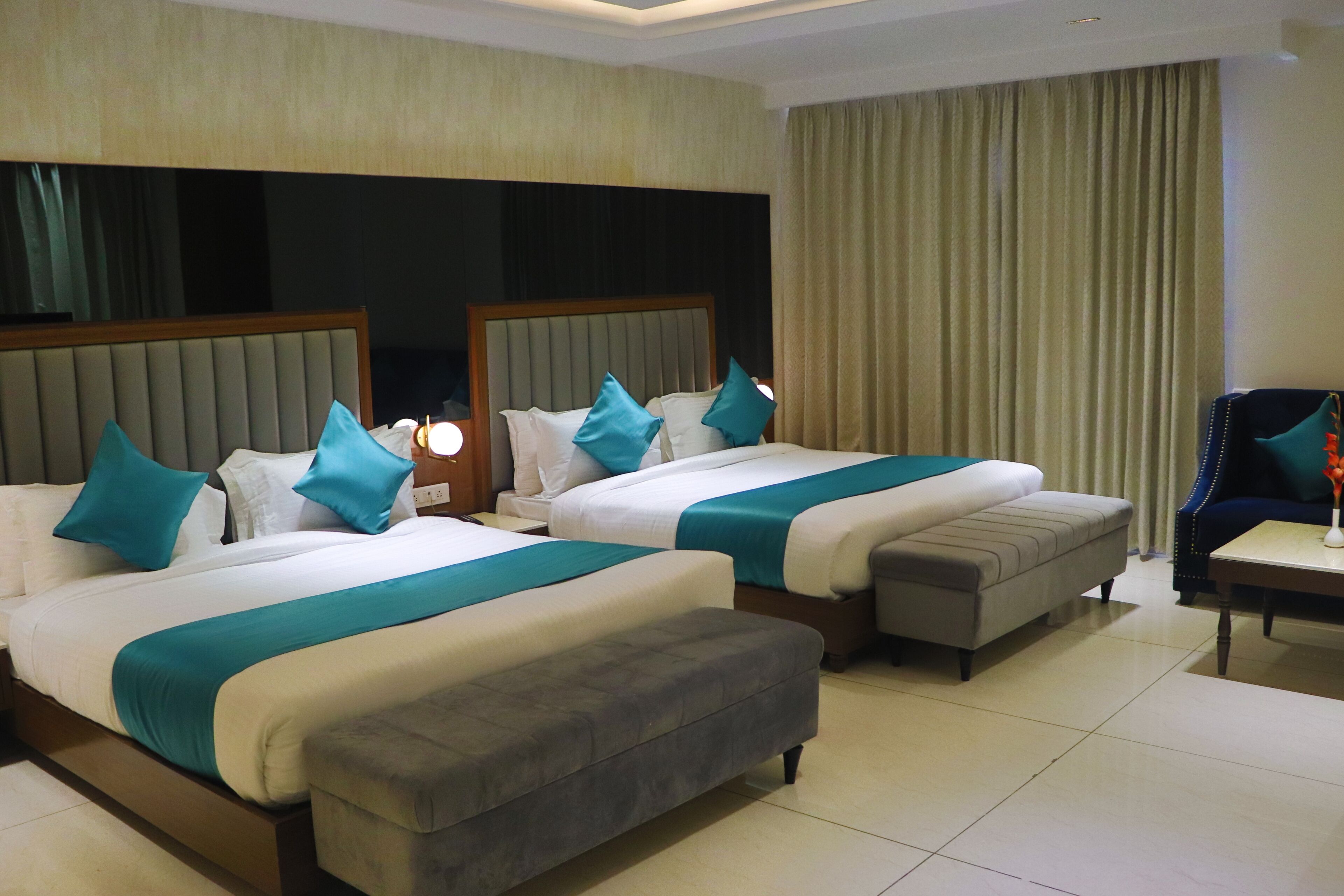A hotel room with two beds, a sofa, a chair, and a small table.