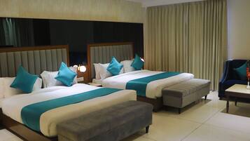 Ein Hotelzimmer mit zwei Betten, einem Sofa, einem Sessel und einem kleinen Tisch.