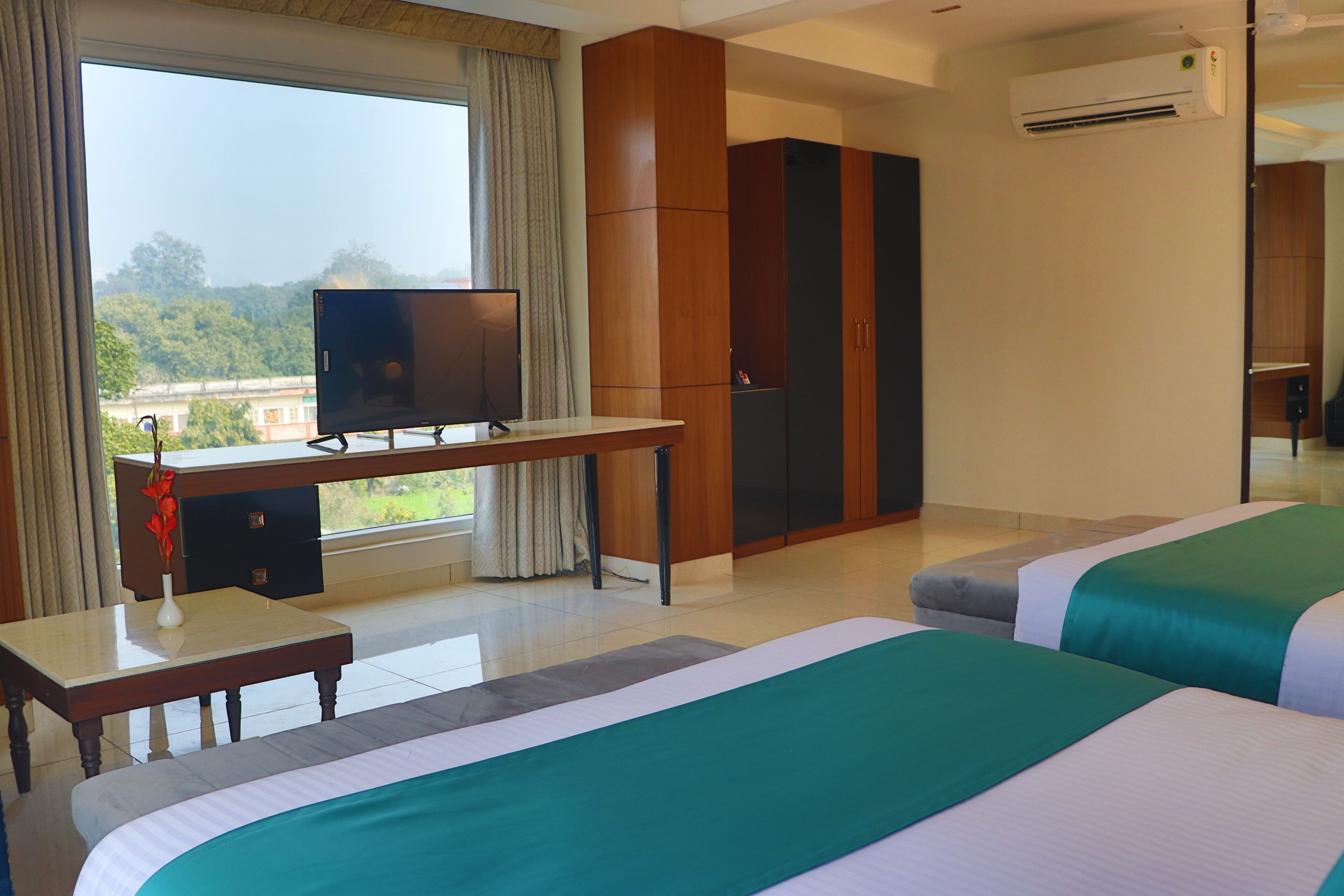 A hotel room with two beds, a desk with a television, and a wardrobe.