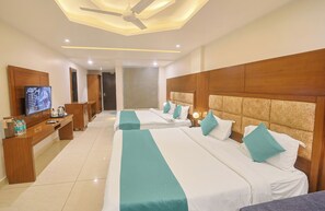 A hotel room with two beds, a TV, a desk, and a mirror. - Hotel Green - Behind Parmarth Niketan (Rishikesh)