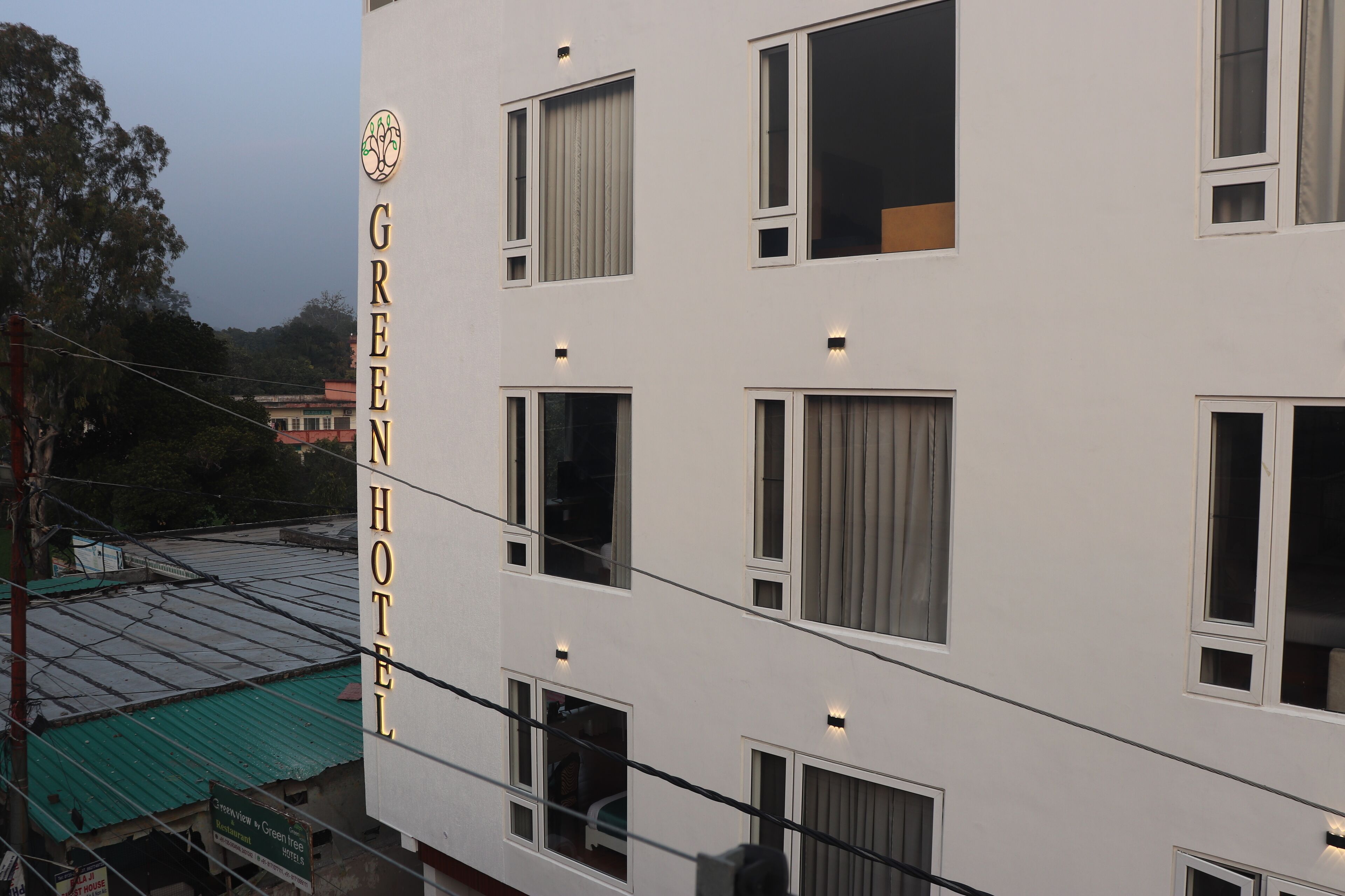 Un immeuble à plusieurs étages dont la façade porte en grand le nom « GREEN HOTEL ».