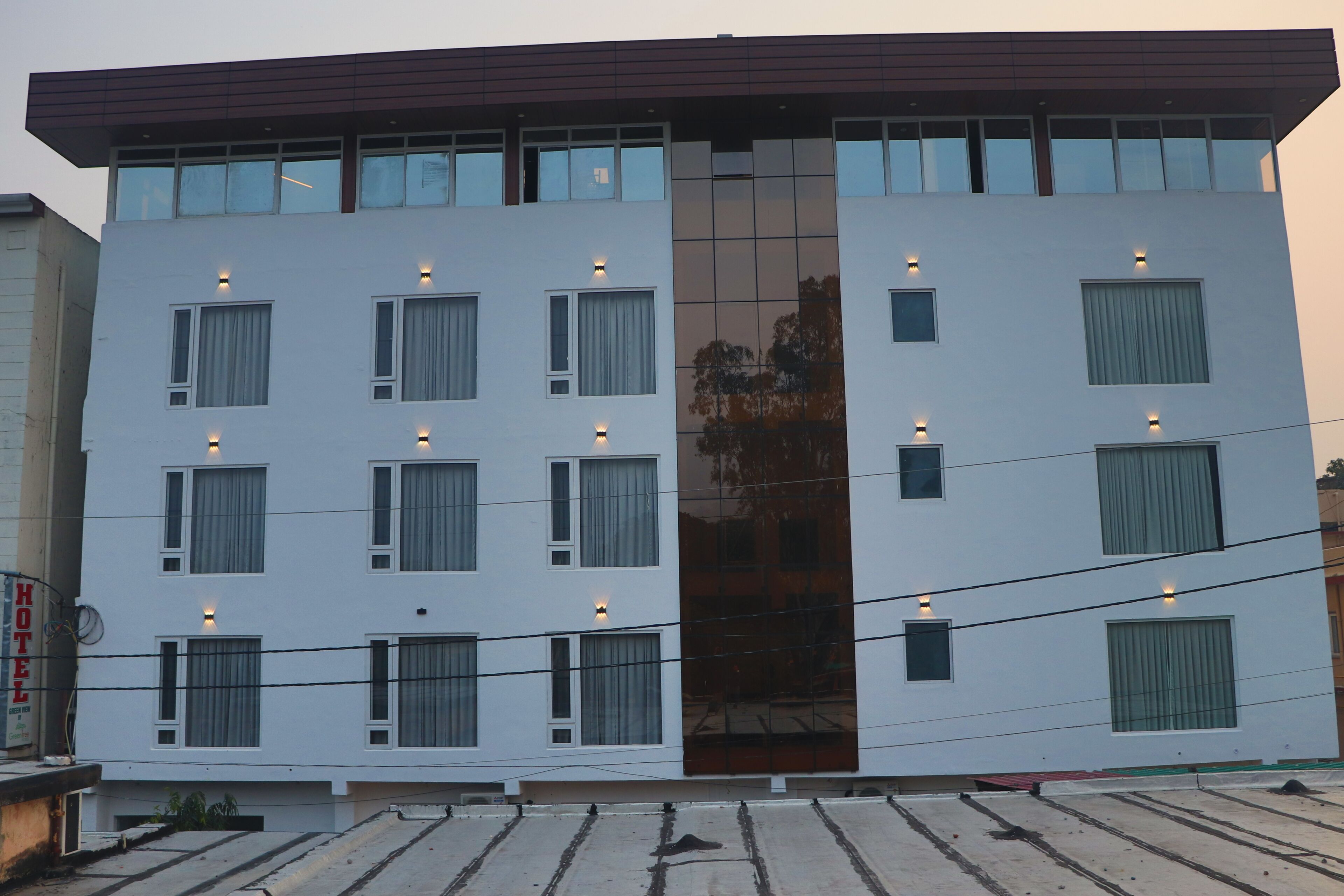 Ein modernes Hotel mit flacher Fassade, zahlreichen Fenstern und einem zentralen, spiegelnden Glasbereich.