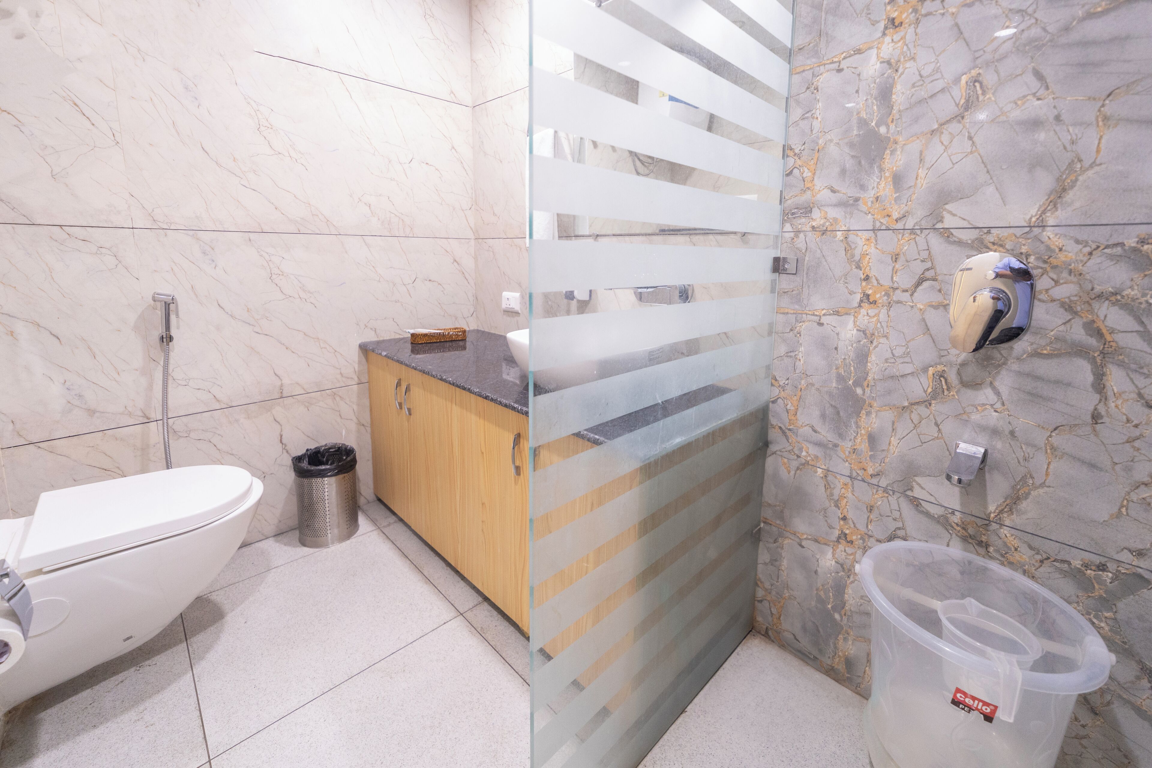 A bathroom with a toilet, a trash can, a sink, and a shower.