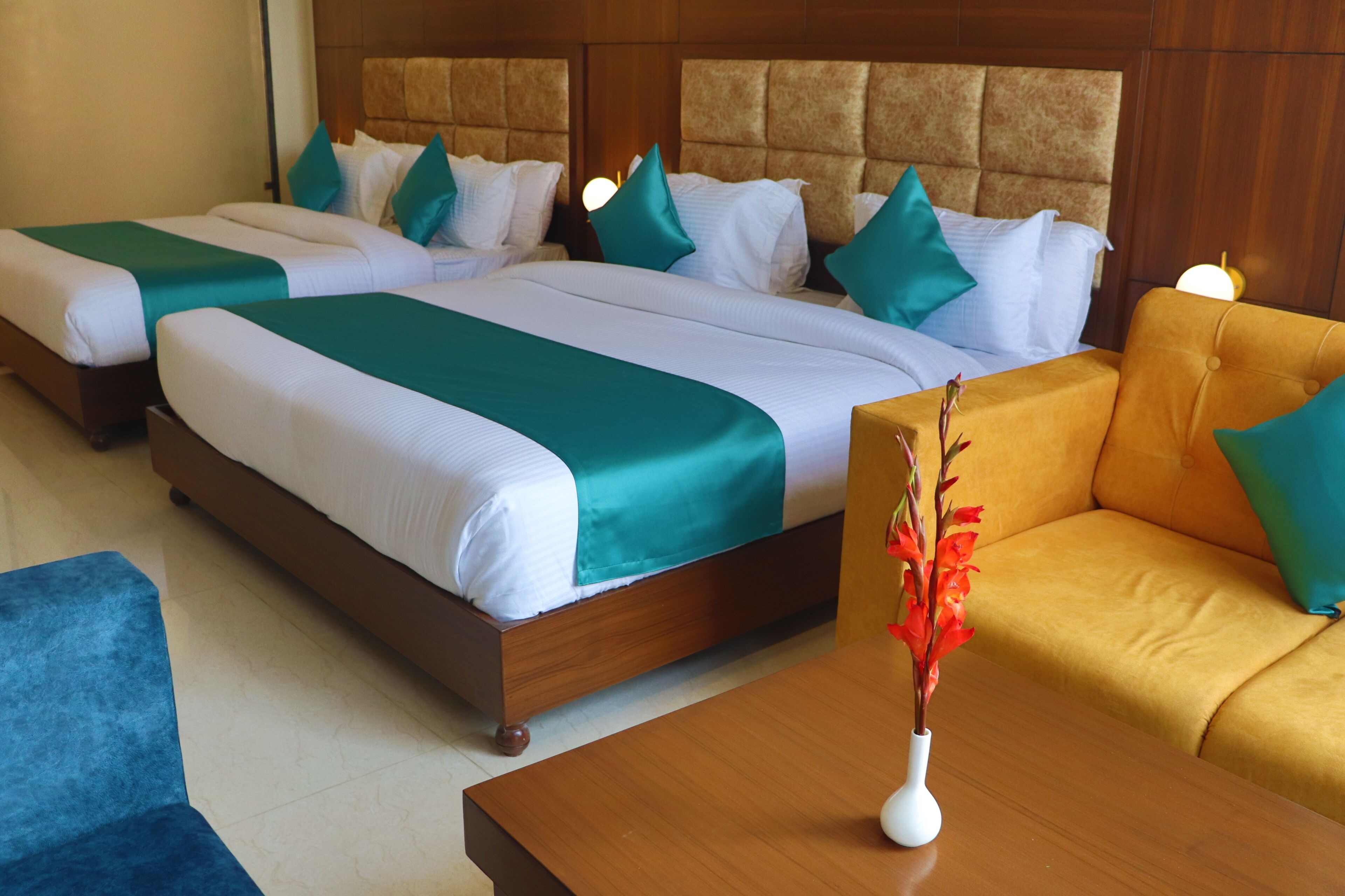 A hotel room with two beds, a sofa, and a wooden coffee table.