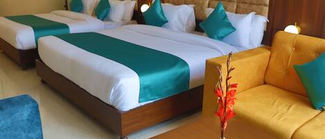 A hotel room with two beds, a sofa, and a wooden coffee table.