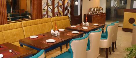 A restaurant with a long dining table, multiple chairs, and a yellow cushioned bench.