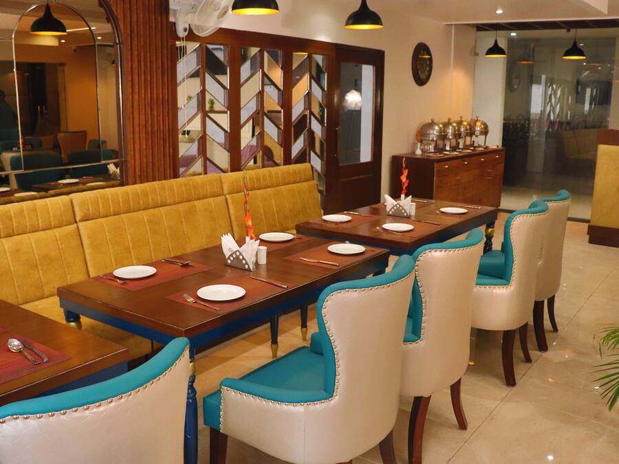 A restaurant with a long dining table, multiple chairs, and a yellow cushioned bench.