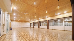 A spacious room with wooden flooring, ceiling fans, and large windows. - Hotel Green - Behind Parmarth Niketan (Rishikesh)