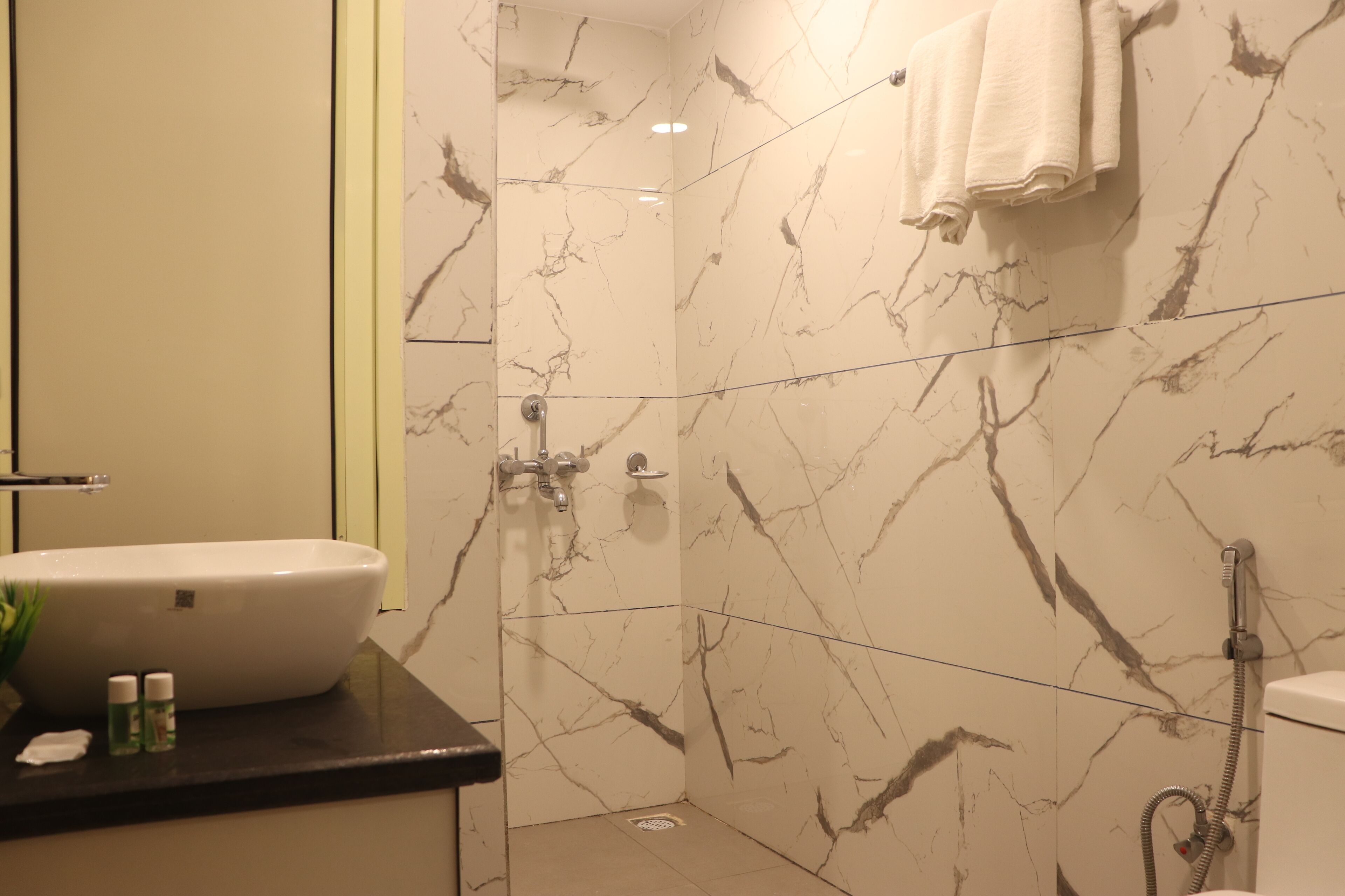 A bathroom with a marble wall, a sink, and a shower.
