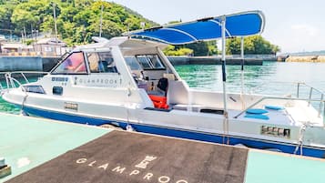 A boat docked at a marina with a name on the side, a covered seating area, and a wakeboard on the deck.