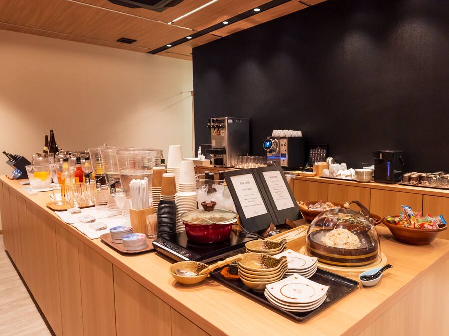 A buffet setup with various food items, beverages, and utensils.