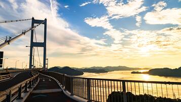 A bridge with a view of a sunset over a body of water and distant mountains.
