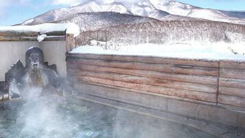 A hot spring area with a wooden wall and a stone sculpture.