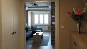 Una puerta abierta que da a una sala de estar con un sofá, una mesa de centro y una planta decorativa.