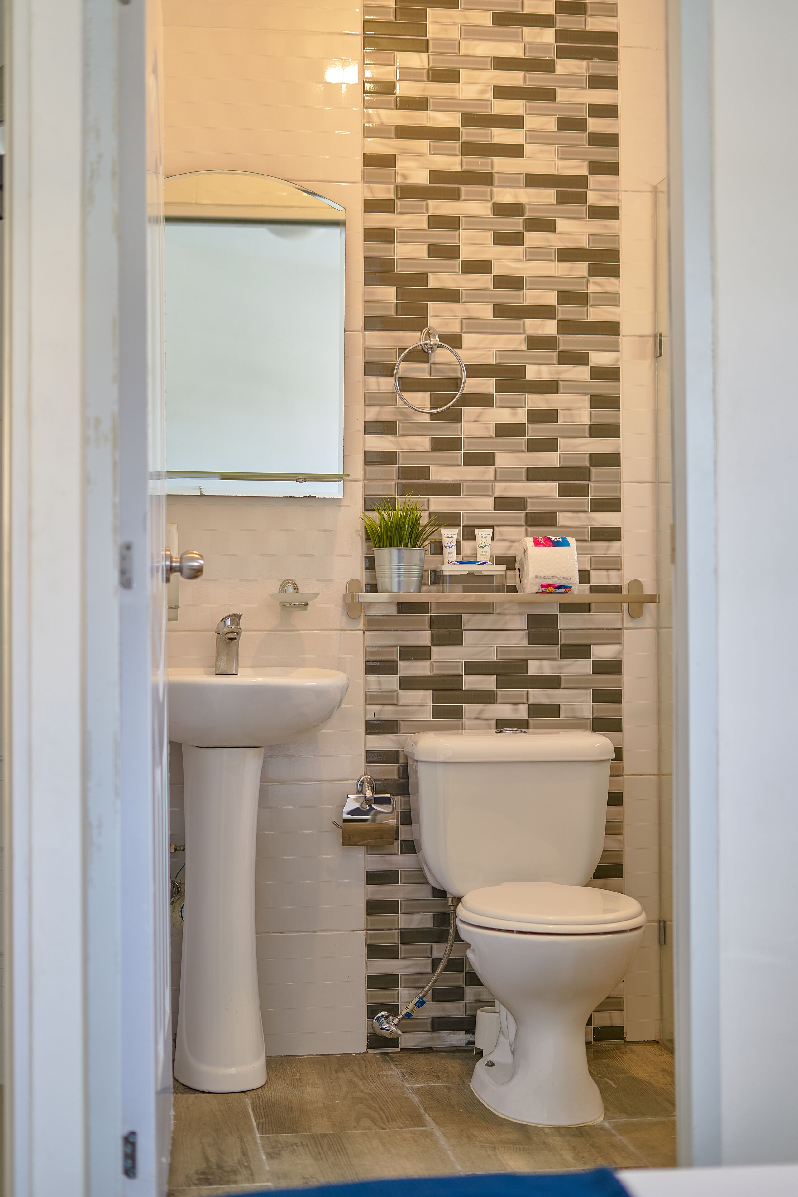 A bathroom with a white sink, toilet, and a tiled backsplash.