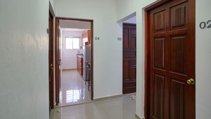 A hallway with doors numbered 04 and 05, leading to a kitchen area with cabinets and a refrigerator.