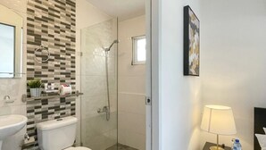 A modern bathroom with a glass-enclosed shower, a toilet, and a sink.