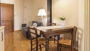 A dining area with a wooden table, four chairs, a vase with flowers, a lamp, and a sofa with cushions. - Casa Carolina by Mmega (Florence)