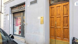 A building with a large wooden double door, a glass storefront, and a car parked on the street. - Casa Carolina by Mmega (Florence)
