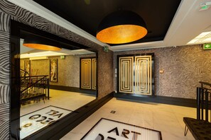 A lobby with zebra-patterned walls, a large black pendant light, and a framed artwork on the wall.