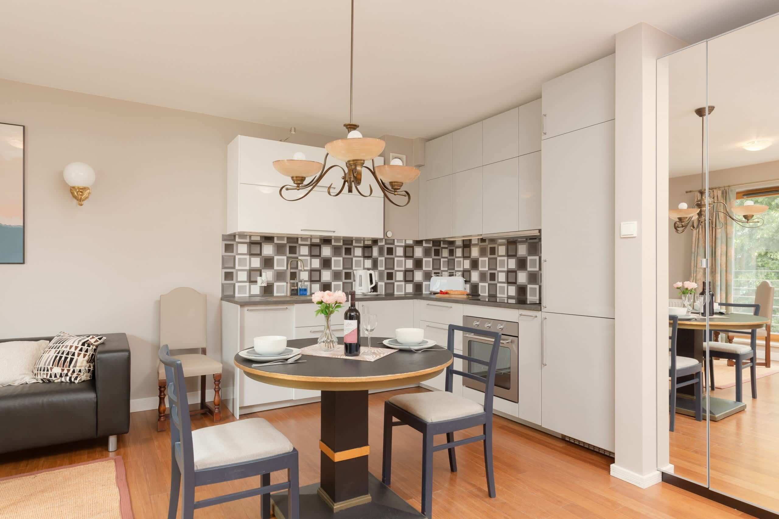 A modern kitchen with a central island, white cabinets, and a tiled backsplash.