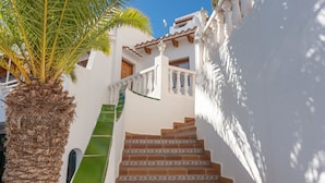 A staircase with patterned tiles, a palm tree, and a white building with a balcony. - Holiday Park Santa Ponsa (Calvia)