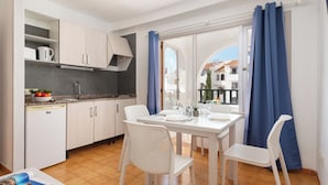 A modern kitchen with white cabinets, a built-in oven, and a dining area with a table set for two. - Holiday Park Santa Ponsa (Calvia)