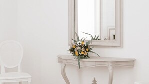 Een witte stoel en een console tafel met een bloemstuk.