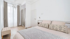 Een slaapkamer met een bed, nachtkastje, stoel, kledingkast en een deur.