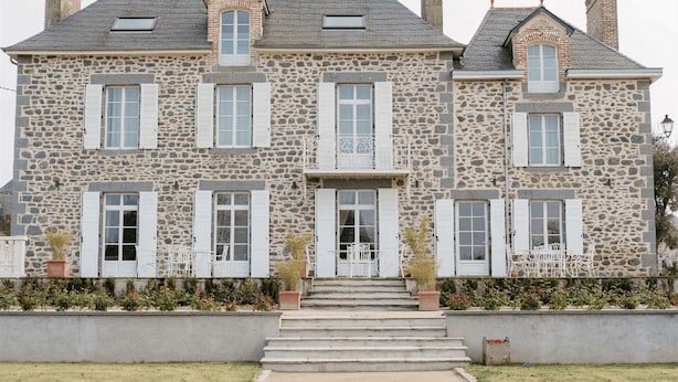 A stone building with multiple windows and a central entrance. - Welcome to Arsene Gardens (TINTÉNIAC)