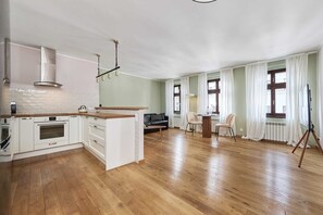 A spacious living area with a kitchen, wooden flooring, a sofa, a dining table, and a tripod. - Elegant Apartment | 500 m to Market Square, City Center of Wroclaw (Wroclaw)