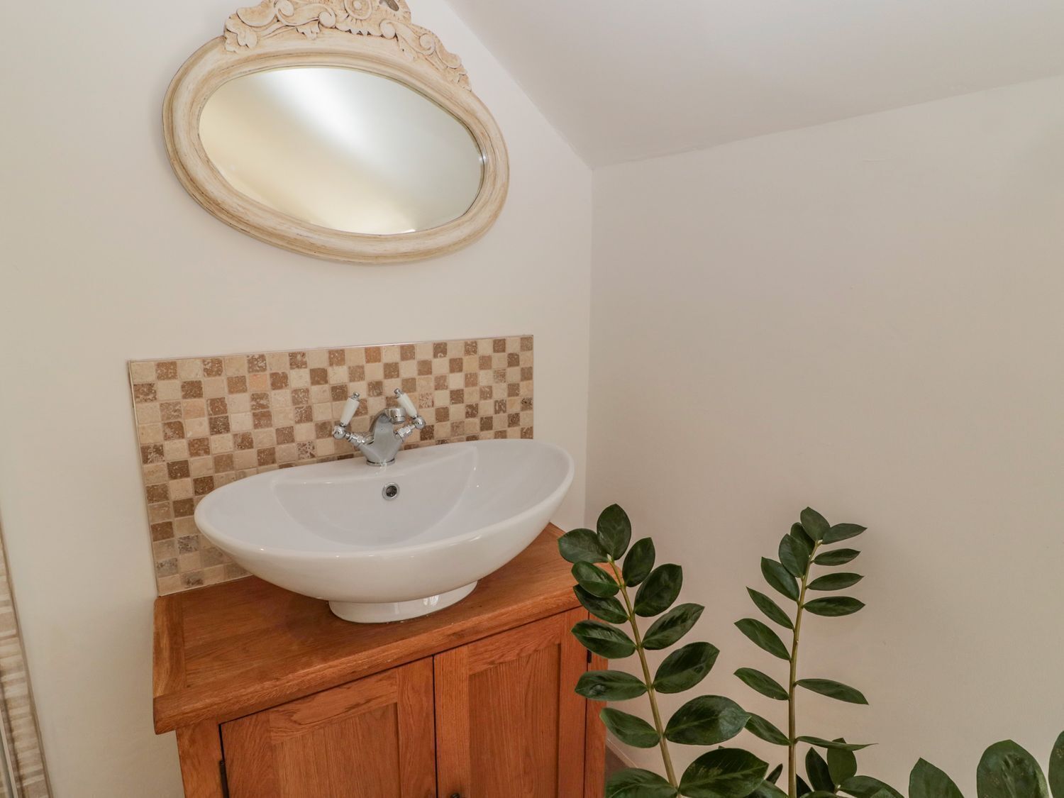 Un baño con un lavamanos blanco, un espejo encima y un respaldo de azulejos a cuadros.
