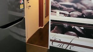 A hotel room with a minibar, a door leading to a hallway, and a wall with a coffee advertisement. - Homely 1 Bedroom Retreat in South Yarra With Balcony (South Yarra)