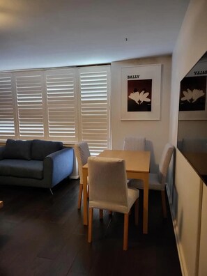 Un salon avec un canapé, une table à manger et des chaises, et un tableau encadré accroché au mur.
