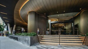 Une entrée moderne, avec une façade incurvée, des marches menant à une porte en verre et une enseigne indiquant « SkyRise ».