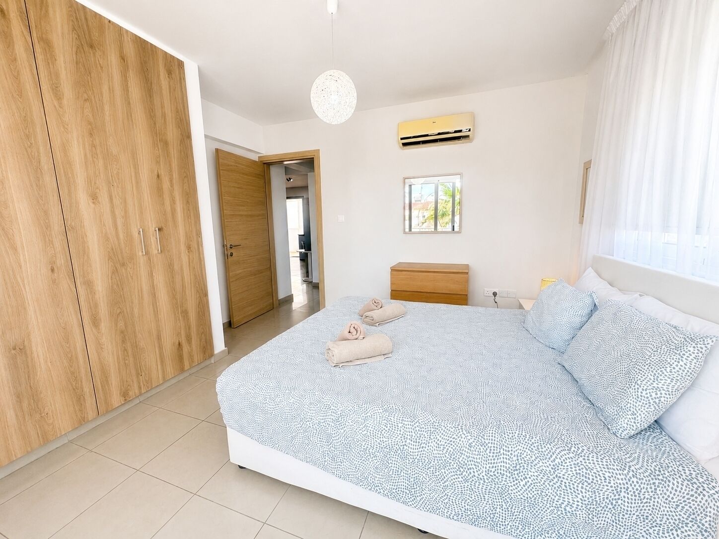 Un dormitorio con cama, armario, mesita de noche y aire acondicionado.